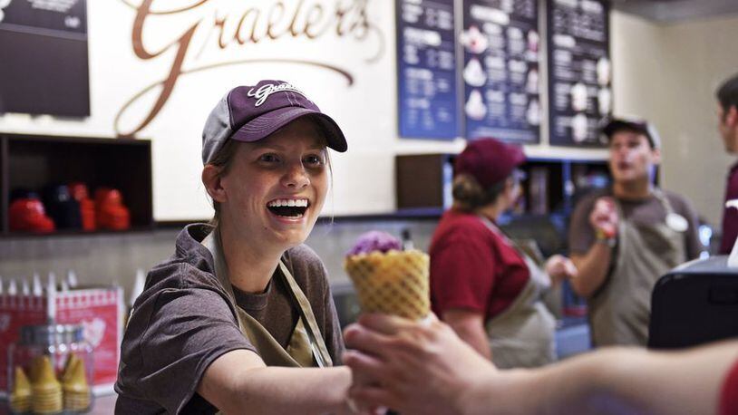 Katie Bowling hands an ice cream cone to a customer during opening day Monday, July 6, 2015, of the new Graeter’s Ice Cream in Oxford. NICK GRAHAM/STAFF