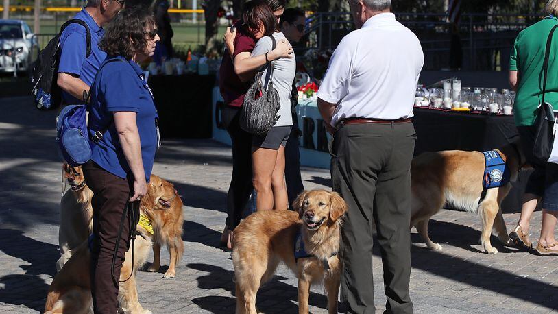 Two women hug while surrounded by comfort dogs at a memorial site to honor victims of the mass shooting at Marjory Stoneman Douglas High School, at Pine Trail Park on February 16, 2018 in Parkland, Florida. Fourteen therapy dogs who helped students were pictured in the school's 2018-19 yearbook.