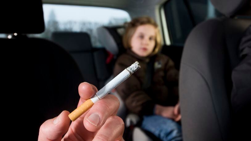 Woman smoking with child in car (stock photo)