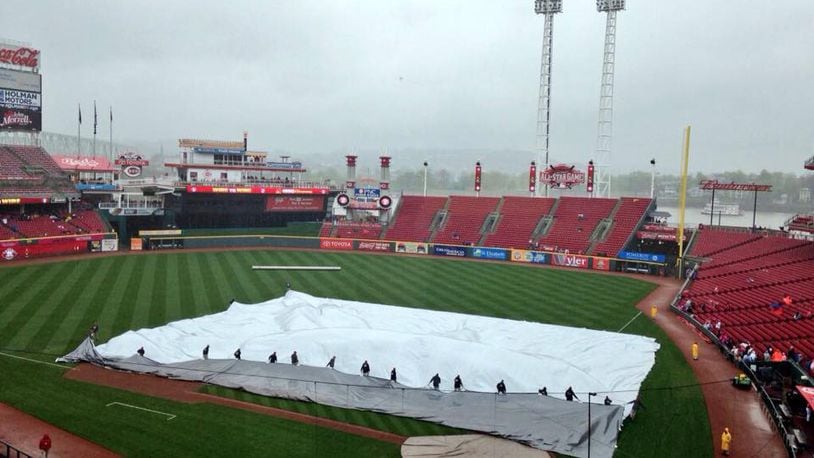 The grounds crew puts the tarp on the field at Great American Ball Park on Saturday. David Jablonski/Staff