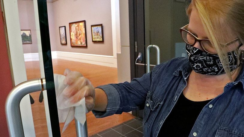 Elizabeth Wetterstroem wipes down door handles on the entry to the galleries at the Springfield Museum of Art. BILL LACKEY/STAFF
