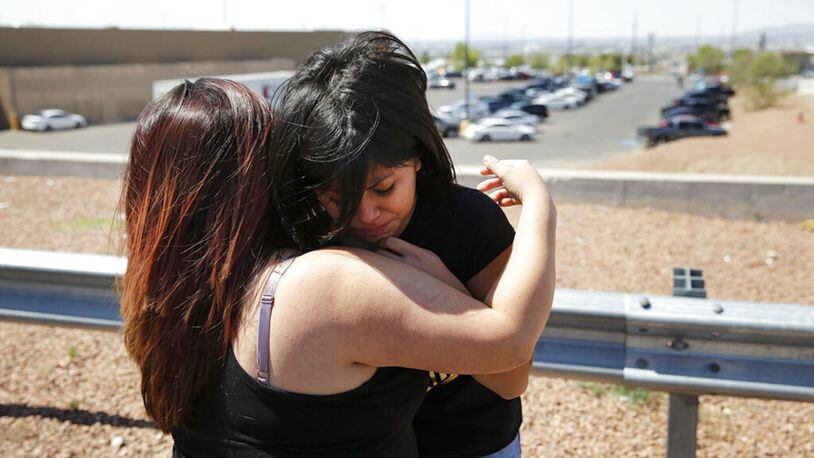 A mother comforts her daughter after she left flowers in memory of the victims of the shooting at the Walmart in El Paso on Aug. 4. The shooting killed more than 20 people.