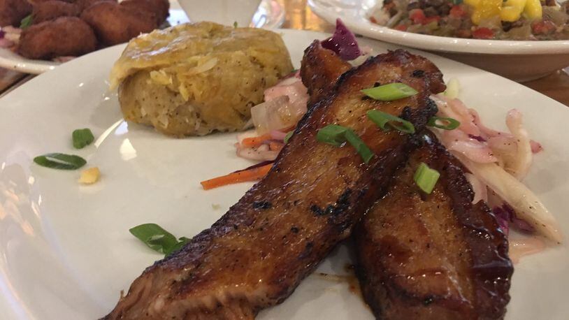 Calypso Pork Belly ($12.99) with Shrimp Pup-a-lickie ($7.49) and pigeon peas and rice ($8.99) in the background. CONTRIBUTED/ALEXIS LARSEN