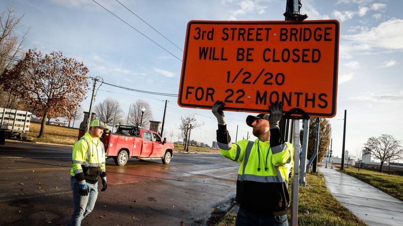 Kevin Kirk, left and Wes Minton remove road closed sign off the westside of the newly rebuilt Third Street bridge Thursday Dec. 2, 2021. JIM NOELKER/STAFF
