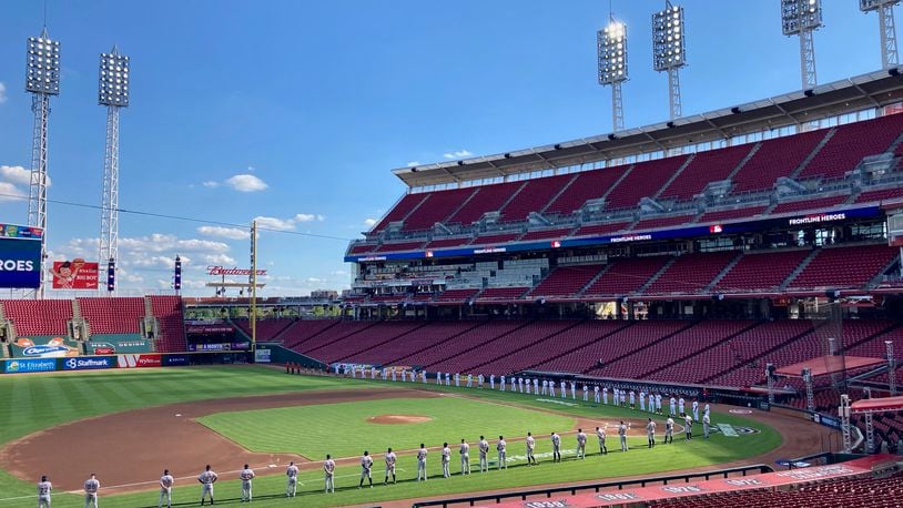 The Reds and Tigers stand during pregame ceremonies on Opening Day on Friday, July 24, 2020, at Great American Ball Park in Cincinnati.