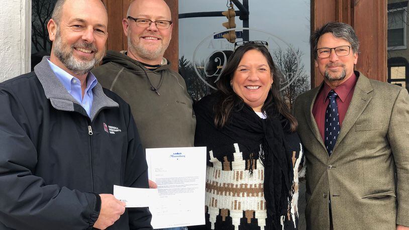 Miamisburg Community Foundation Vice President Shon Myers (left) and foundation President Greg Bell (right) present a check to A Taste of Wine owners Chris and Urmila Holloway Friday, Jan. 8, 2021. The check was one of three distributed to area eateries by the foundation's newly established Louis Epperson Restaurant Rescue Fund.