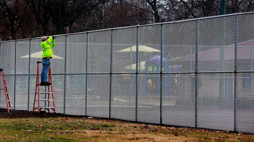 An employee of Hunt's Fencing works on the new fence aroung the Snyder Park tennis and pickleball courts Wednesday, Jan. 11, 2023. The courts have also been resurfaced for the growing pickleball population in Springfield. BILL LACKEY/STAFF