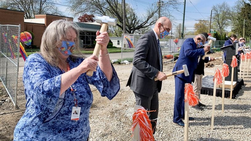 Francesca Hary, left, manager of the Dayton Metro Library's Burkhardt Branch, drives a stake Friday marking the location of the new branch's front door. CHRIS STEWART / STAFF