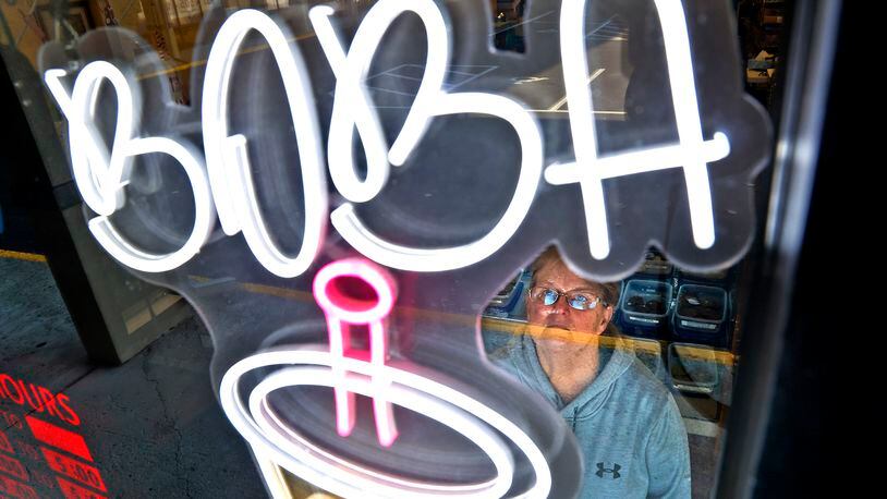 Shari Donnelly, owner of It's Your Party Bakery, looks up a the new neon sign advertising Boba Tea Tuesday, Nov. 22, 2022 in her bakery window. BILL LACKEY/STAFF