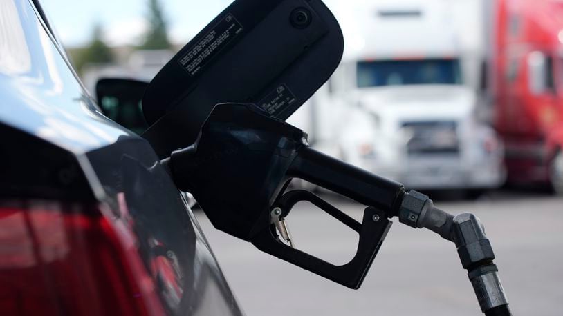 A pump handle hangs from a car at a gas station as motorists take to the road to start the Memorial Day weekend, Thursday, May 27, 2021, near Cheyenne, Wyo. (AP Photo/David Zalubowski)