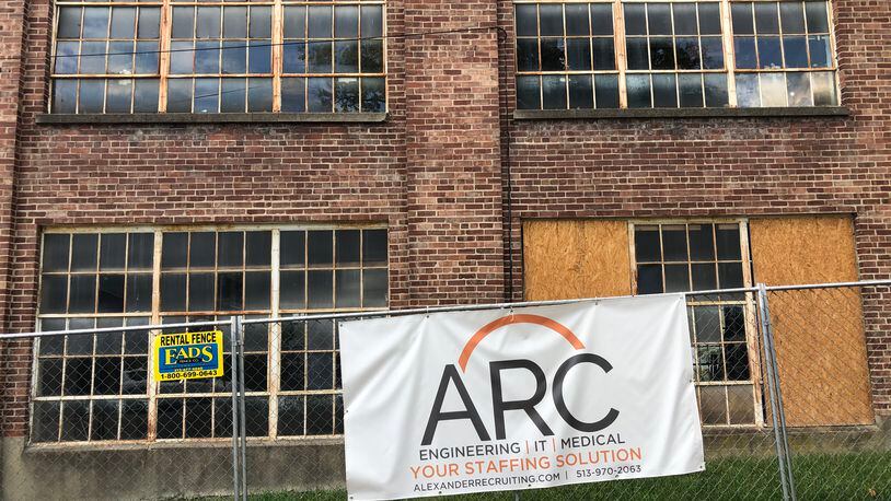 A sign for Alexander Recruiting hangs from a security fence around a former shoe factory the family has proposed for a  $12 million redevelopment.