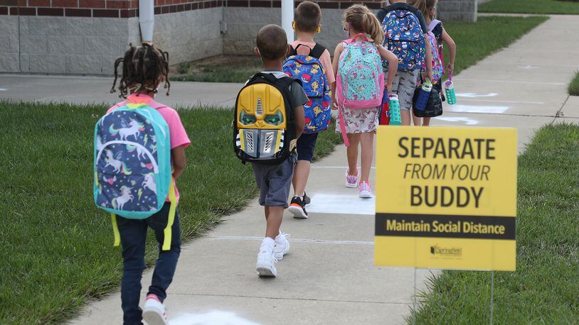Students practice social distancing as they walk into Simon Kenton Wednesday for the first day of school. BILL LACKEY/STAFF
