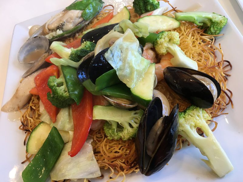A pan-fried noodle cake topped with fresh cooked vegetables and seafood ($15) including a generous number of shrimps, scallops, mussels and clams served at Sugar & Spice Asian Bistro on Brown Street. Contributed photo by Alexis Larsen