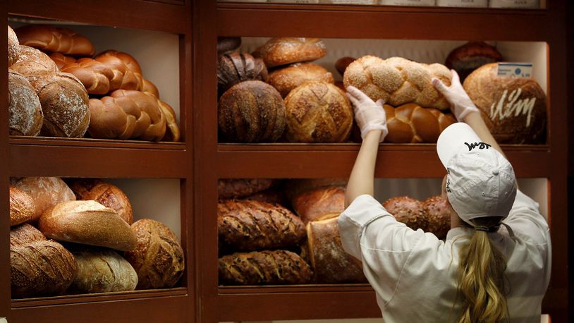 In this photo from 2015, a retail bakery associate at Dorothy Lane Market arranges over a dozen varieties of bread at the Washington Twp. store.
