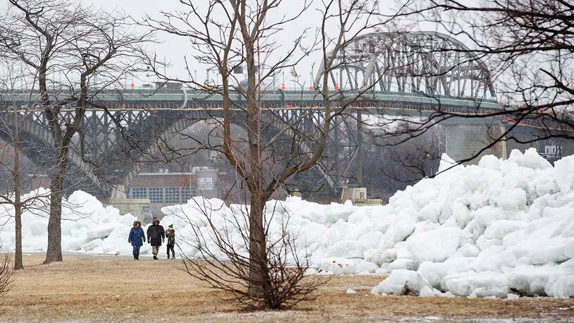 A family walks near a massive build up of ice that was pushed onto the shore of Mather Park in Fort Erie, Ont., Monday, February 25, 2019. A windstorm Sunday broke an ice boom in Lake Erie and allowed the ice, which was floating on the water at the mouth of the Niagara River, to shove over the retaining wall and move onto the shore and the roadway above.