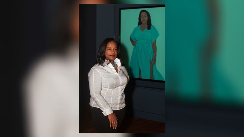 Tuliza Fleming stands in front of a portrait of Breonna Taylor, the Black woman shot and killed by Louisville police officers in 202. The portrait is by Amy Sherald, the artist who painted the official portrait of First Lady Michelle Obama. Fleming, who grew up in Yellow Springs, is a curator at the Smithsonian's National Museum of African American History and Culture. PHOTO/NATIONAL MUSEUM OF AFRICAN HISTORY AND CULTURE
