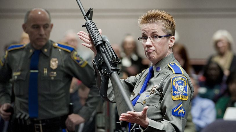 In this Jan. 28, 2013, file photo, firearms training unit Detective Barbara J. Mattson, of the Connecticut State Police, holds up a Bushmaster AR-15 rifle for a demonstration during a hearing at the Legislative Office Building in Hartford, Conn.