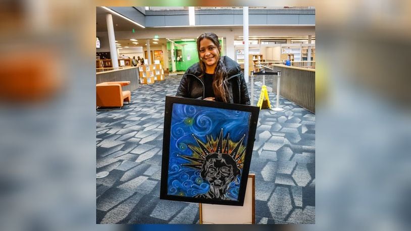 Elimar Runza holds her painting in the Dayton Metro Library Wednesday October 26, 2022. Runza along with other new Americans' work is being exhibited at the library's main office on East Third Street through Dec. 31. Runza is from Venezuela. JIM NOELKER/STAFF