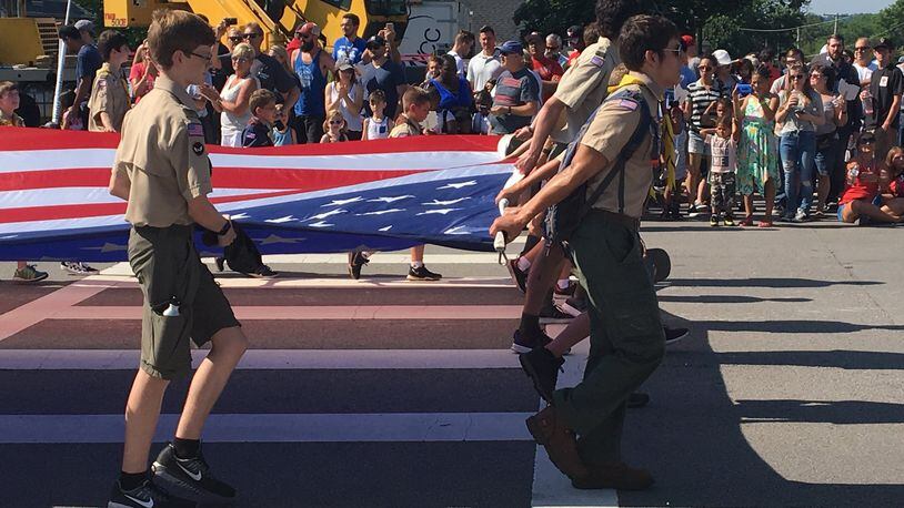 A troop of boy scouts carry an American flag in the parade at the 45th Americana Festival in Centerville on Wednesday. The annual festival drew thousands of visitors despite high temperatures.