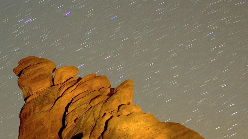 A Geminid meteor streaks diagonally across the sky against a field of star trails over one of the peaks of the Seven Sisters rock formation early December 14, 2007 in the Valley of Fire State Park in Nevada. The meteor display, known as the Geminid meteor shower because it appears to radiate from near the star Castor in the constellation Gemini, is thought to be the result of debris cast off from an asteroid-like object called 3200 Phaethon. The shower is visible every December.