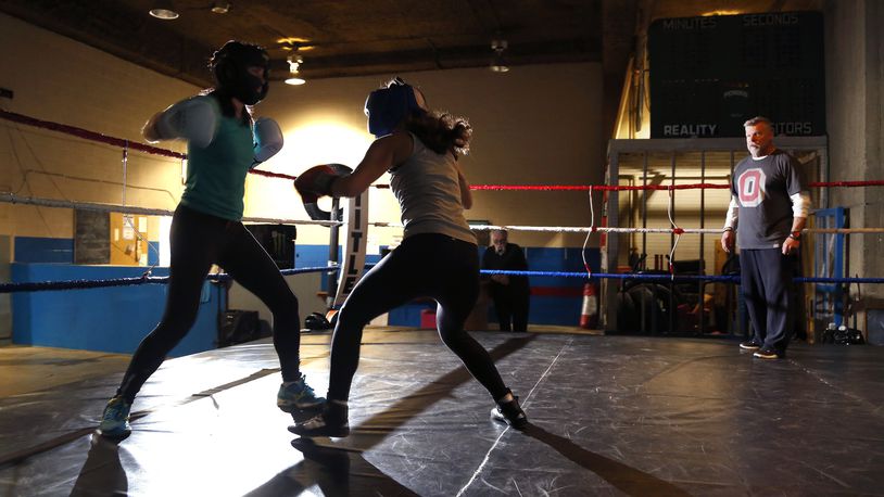 Lauren Amongero of Oakwood and Aimee Pezo of Dayton work out at Drake's Downtown Gym under the watchful eye of gym owner John Drake (right). The two women will meet in a boxing ring during an adult amateur exhibition boxing match Saturday April 8.  LISA POWELL / STAFF