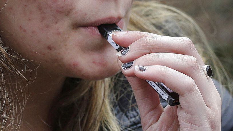 File photo shows a high school student uses a vaping device near a school campus in  Mass. Massachusetts Gov. Charlie Baker is declaring a public health emergency and ordering a four-month temporary ban on all vaping products in the state.