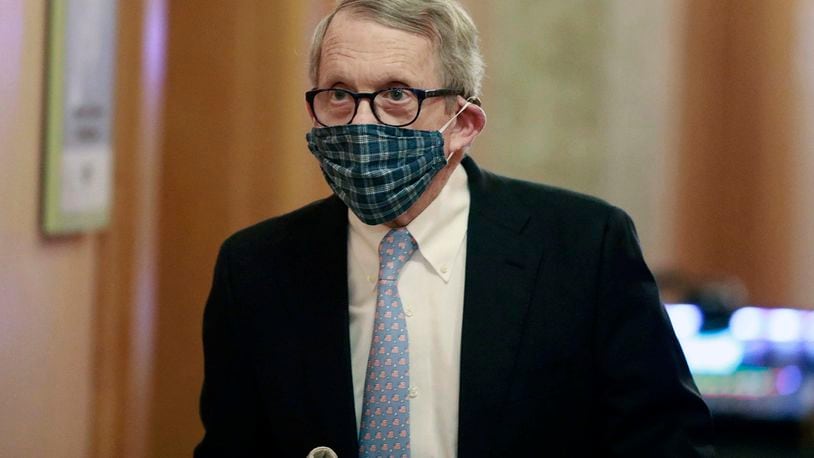 FILE - In this April 16, 2020, file photo wearing his protective mask made by his wife, Ohio Gov. Mike DeWine walks into his daily coronavirus news conference at the Ohio Statehouse in Columbus, Ohio. (Doral Chenoweth/The Columbus Dispatch via AP, File)