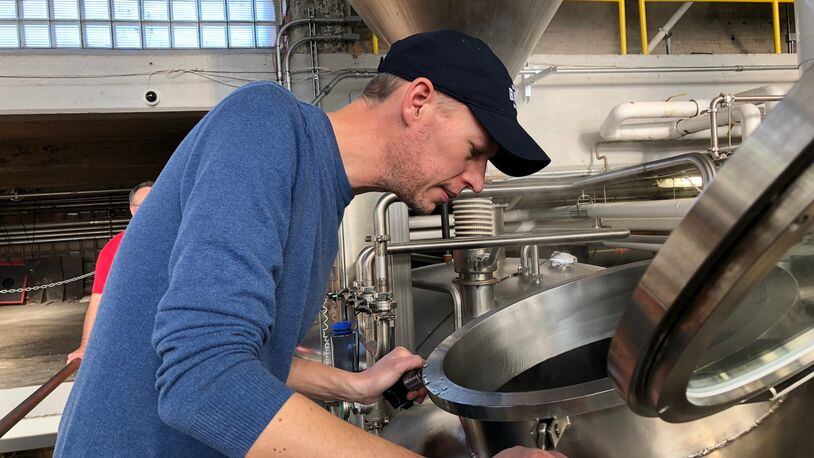 Andy Melchers, winner of a home-brewing competition, checks on the early stages of brewing his winning recipe at Warped Wing Brewing Company on Friday, Jan. 26. MARK FISHER/STAFF