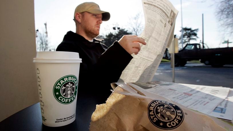 ** FILE ** J.J. Geise reads a paper as he treats himself to coffee and a baked good at a Starbucks coffee shop in Seattle in this Jan. 25, 2008 file photo. Starbucks Corp. is teaming up with AT&T Inc. and will start offering a mix of free and paid wireless Internet service in many of its U.S. coffee shops, beginning this spring. (AP Photo/Elaine Thompson, file)