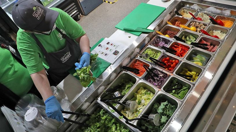 A Fresh Abilities associate builds a customer’s salad from a wide variety of fresh items Wednesday at COhatch. BILL LACKEY/STAFF