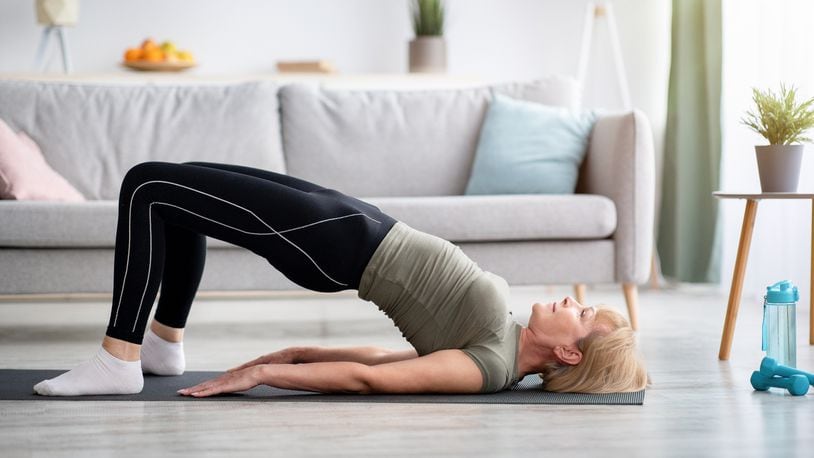 A woman is seen doing a half bridge yoga pose, strengthening her abs muscles indoors, copy space. ISTOCK BY GETTY IMAGE