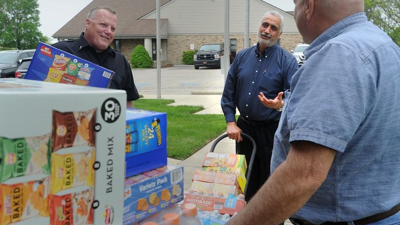 Miami Twp. restaurateur Surjit Singh Mattu., center, expresses his appreciation of the Miami Township Police Department by dropping off snacks and drinks Wednesday, April 28, 2021. Mattu talks with Lt. Mike Siney, left and John Brun while making his delivery. MARSHALL GORBY\STAFF