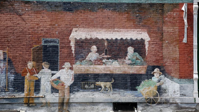 Though the paint has faded a market scene can still be scene in this mural n the side of the brick building at Third Street and Linden Avenue in Dayton. LISA POWELL / STAFF
