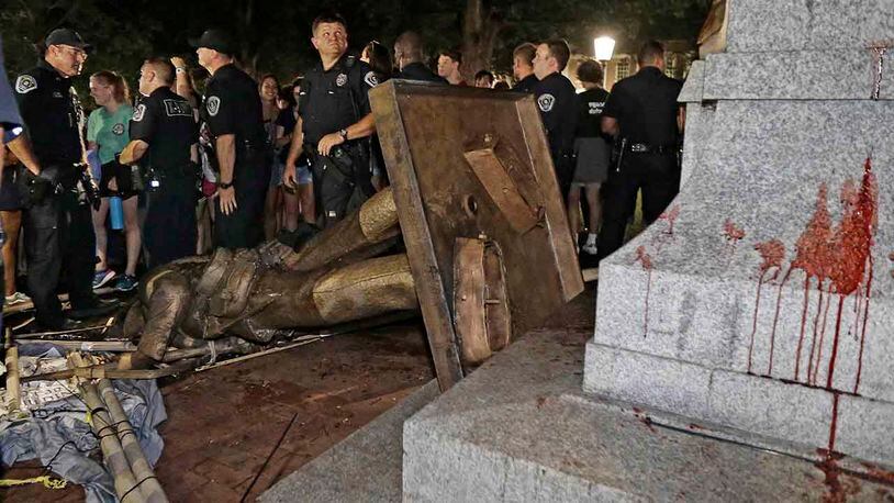 Police stand guard after the Confederate statue known as Silent Sam was toppled by protesters on campus at the University of North Carolina in Chapel Hill, N.C., Monday, Aug. 20, 2018. (AP Photo/Gerry Broome)