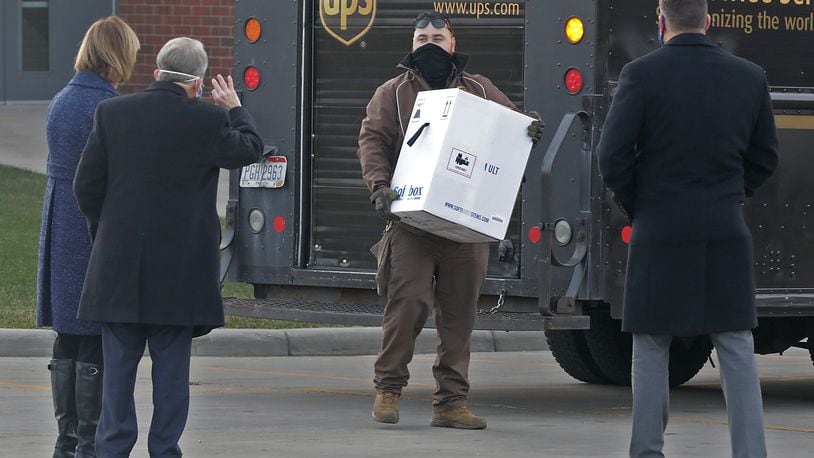 Gov. Mike DeWine and his wife, Fran, along with Springfield Regional Medical Center President Adam Groshans, right, greet a UPS driver as he delivers the first COVID-19 vaccine at the hospital Tuesday, Dec. 15, 2020.  BILL LACKEY/STAFF