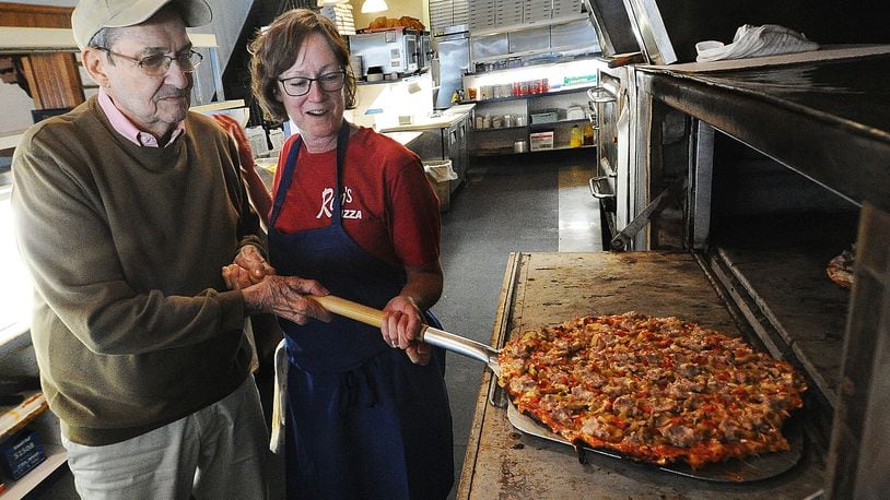 Ron Holp and his daughter, Abbie Romero, remove a pizza from the oven at Ron's Pizza in downtown Miamisburg Thursday, Jan. 5, 2023. The business is in the process of wrapping up remodeling that has taken more than a year. MARSHALL GORBY/STAFF