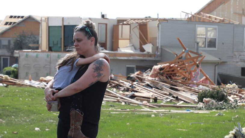 Meghan Porter and daughter Gemma,6, of Beavercreek stand in front of a damaged apartment complex. Porter said her childhood home in Beavercreek was destroyed. BILL LACKEY/STAFF PHOTOGRAPHER