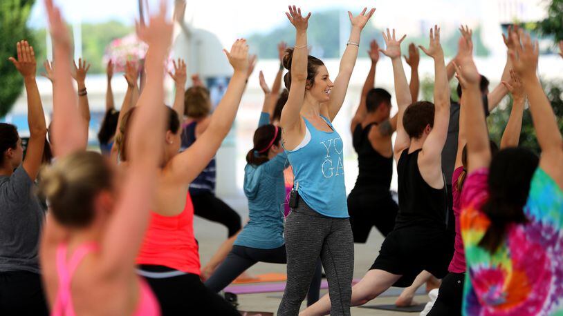Tori Reynolds, a Dayton area yoga instructor, leads more than 80 people in a yoga class at RiverScape Metro Park. During the month of May Fitness in the Park will go virtual.  LISA POWELL / STAFF FILE PHOTO