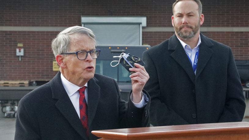 Gov. Mike DeWine reminds residents that they still need to wear a mask last week as Springfield Regional Medical Center President Adam Groshans listens shortly after the first vaccine arrives at the hospital. BILL LACKEY/STAFF