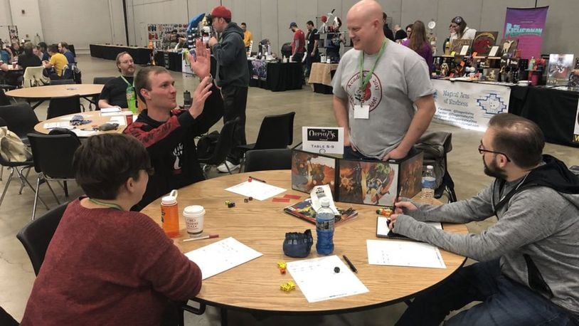 A group of friends plays a role-playing game while vendors sell their wares in the background. AcadeCon 2018 will take place Friday, November 9 through Sunday, November 11 at Dayton Convention Center. CONTRIBUTED