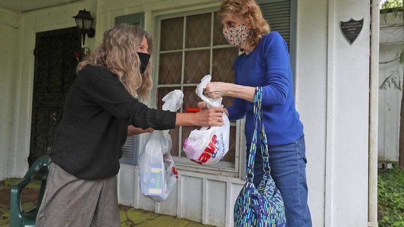 Becky Michels, from United Senior Services, right, delivers a grocery order to Gail Keen at her home Friday. BILL LACKEY/STAFF