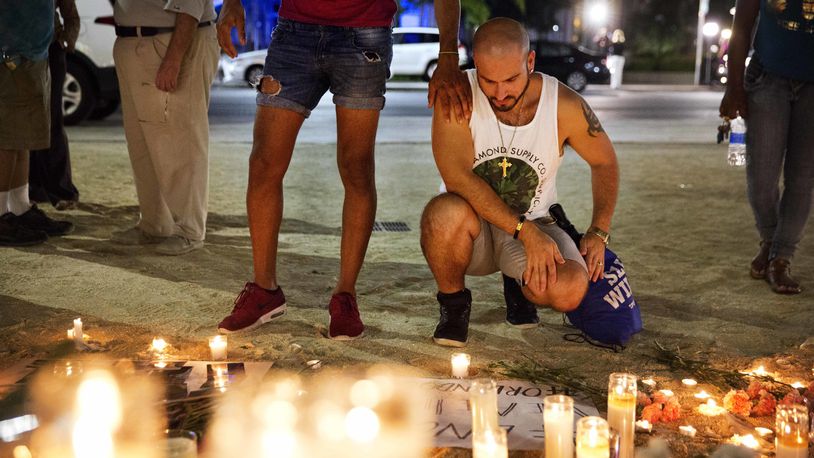Ronny Torres, right, is comforted by Zaid Hinds, as they visit a makeshift memorial for the victims of a mass shooting at the Pulse nightclub Monday, June 13, 2016, in Orlando, Fla. Hinds and Torres lost 12 friends in the shooting. (AP Photo/David Goldman)