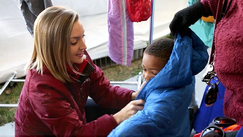 WDTN-TV anchor Brooke Moore helps a young boy bundle up in a winter jacket. Coats for men, women and children were collected for the annual Coats for Kids drive. CONTRIBUTED