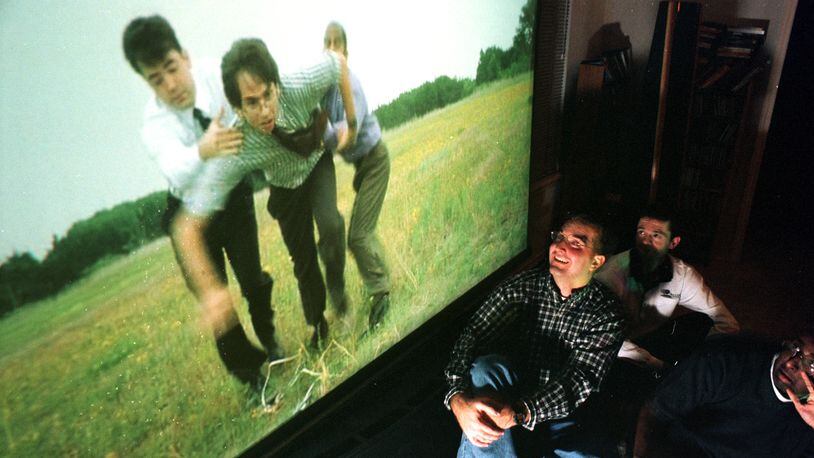 (left to right) Roomates Dylan Hester, Keith Coffey, and Nelson Jesudas watch their favorite scene from the movie Office Space on Hester's huge 8 foot wide screen.  Parts of the film were shot outside Cirrus Logic, where the three work.  Peter Yang/AAS