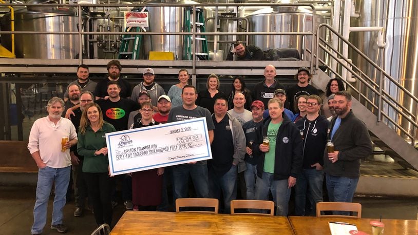 Members of the Dayton Brewery Alliance gathered Friday afternoon at Warped Wing Brewing Company in downtown Dayton to present a check for $65,454 to the Dayton foundation’s tornado-relief fund. The money was raised entirely from the sales and contributions of #DaytonStrong IPA, a special collaborative brew among local breweries. MARK FISHER/STAFF