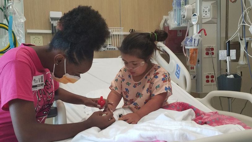 Alanna Wall (left) is shown polishing nails for a hospitalized child. She started Polished Girlz when she was 10 years old. CONTRIBUTED
