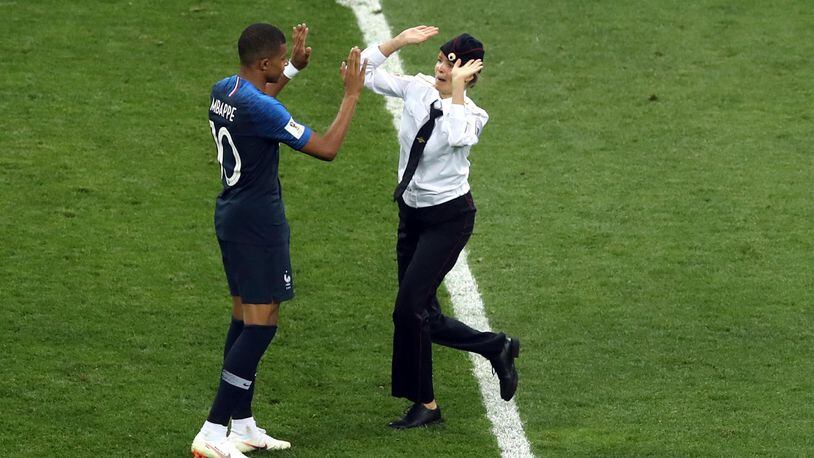 A woman who invaded the pitch approaches France's Kylian Mbappe during the final match between France and Croatia at Sunday's World Cup final.