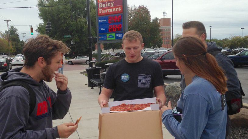 UD student Mark Due and UC student Jerod Webber hand out pizza Friday near UD for ResponsibleOhio. Photo by Amelia Robinson.