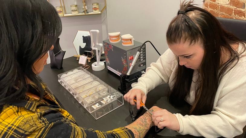 Golden Hour Piercing in Dayton’s Oregon District is now offering permanent jewelry, tooth gems and hair tinsel. Pictured is Hannah Minor. NATALIE JONES/STAFF