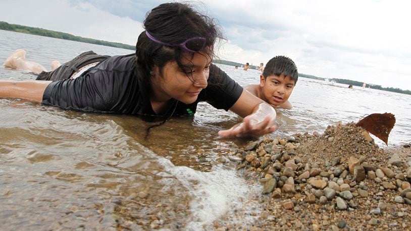 Perla Manzano, 14, and her brother, Juan, 9, pile up rocks along the shore line as they play in the water at the Buck Creek State Park beach Monday, June 19, 2017. Bill Lackey/Staff